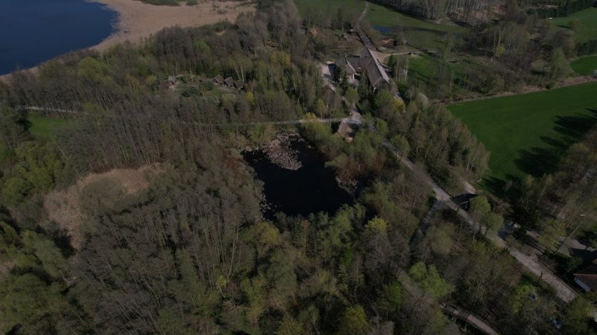 A breathtaking aerial view capturing forests, roads, and a scenic village beside a tranquil lake.